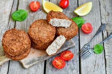 Home made  pork meatballs with  fresh cherry tomatoes on wooden rustic background. Deep fried minced  meat patties on cutting board.
