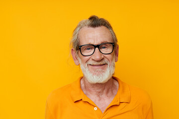 an elderly man with glasses in a yellow t-shirt with glasses close-up