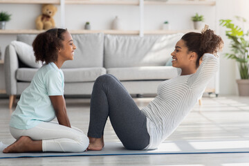 Joyful black mother and kid in sportswear training together