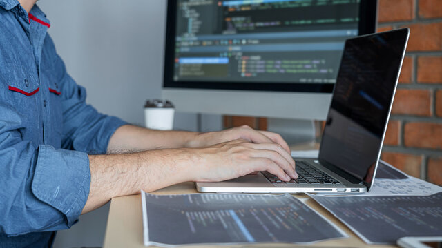 Young Professional programmer working at developing programming and website working in a software develop company office, writing codes and typing data code, Programming with HTML, PHP and javascript