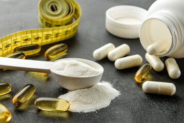 Measuring spoon with creatine close-up. Creatine, BCAA capsules and omega-3 on a dark background.