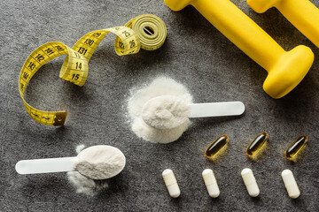 Sports supplements with dumbbells and a tailor's meter close-up.