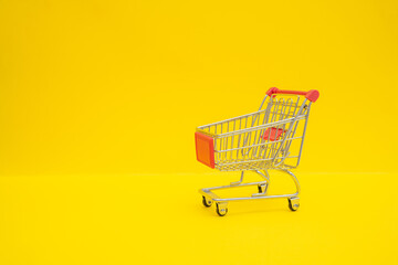 Small steel shopping trolley on yellow surface