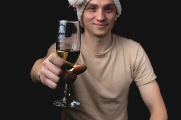 Handsome young man with glass of champagne over isolated black background.