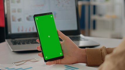 Close up of woman holding isolated green screen vertically on phone. Company worker using mock up...