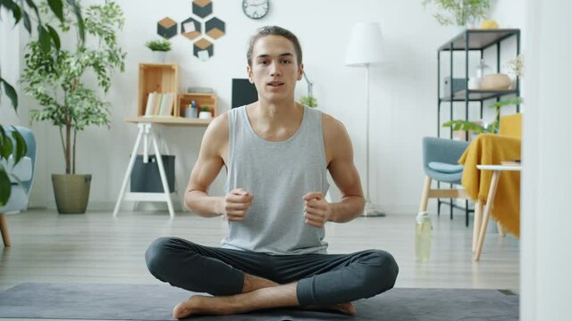 Portrait of yoga vlogger greeting followers with namaste then teaching asana recording tutorial at home. Vlogging and sports concept.