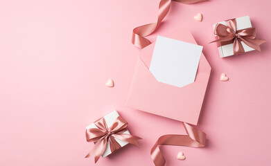 Top view photo of saint valentine's day decor two white gift boxes with pink bows small hearts curly silk ribbon and open pink envelope with letter on isolated pastel pink background with blank space