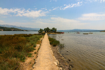 Schmaler Fußweg über das Wasser zur Inselkirche von Novigrad in Dalmatien