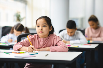 Portrait of asian girl sitting in classroom and writing