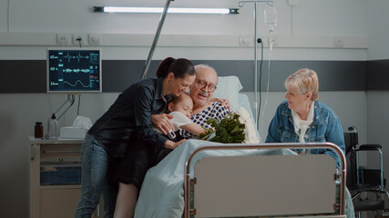 Child and daughter of sick patient coming to visit in hospital ward. Retired man with disease...