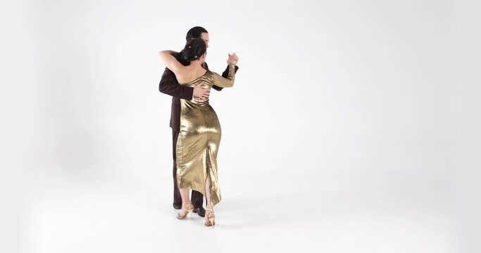 Couple of professional dancers in elegant suit and dress dancing tango on white background.