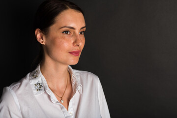 Portrait, studio shot of a smiling pretty attractive attractive young middle-aged girl, on a dark background