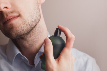 Handsome unshaven man applying perfume on neck, closeup. Space for text
