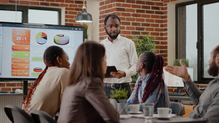 Obraz premium Company employee explaining charts presentation on monitor to plan project for financial development and growth. Business man meeting with colleagues to work on marketing strategy.
