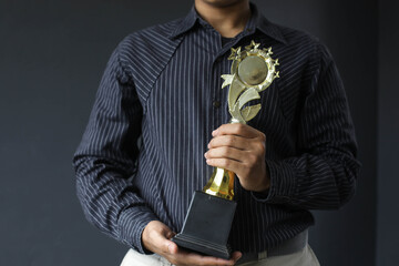 Employee holding award trophy for achievements isolated on gray background