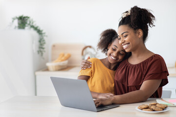 Cute black mother and kid using laptop together