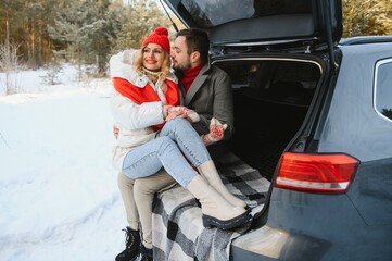 Fototapeta na wymiar lovely smiling couple sitting in car trunk in winter forest