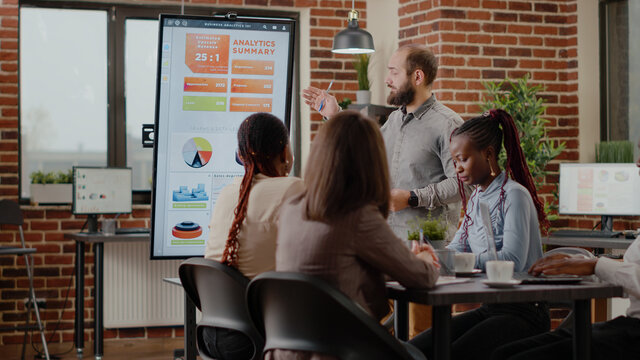 Business man discussing company growth with analysis on monitor, presenting statistics charts to work on project planning and marketing strategy. Employee working with colleagues.