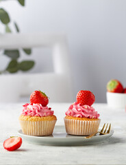 Two cupcakes with strawberries on a plate