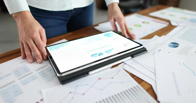 Business woman using a tablet computer and statistical charts conducts audit