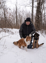a guy walks in a snowy forest with his dogs