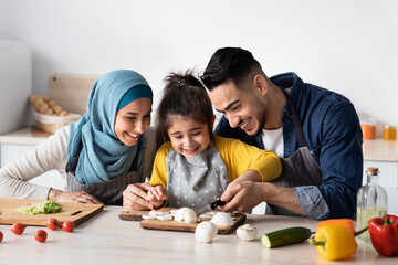 Happy Arab Mom And Dad Teaching Their Little Daughter How To Cook