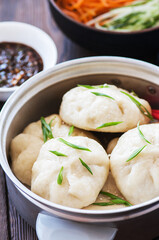 Chinese steamed bun with meat filling served with fresh vegetables and soy sauce.