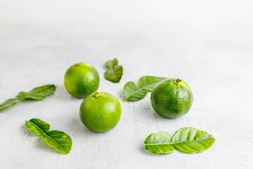 fresh green lime and lime leaves on white wooden table