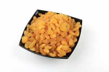 Dried raisins in a dark plate isolated on a white background.