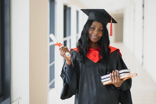 beautiful young afro american graduate holding diploma - a young woman in a graduation gown and cap 
