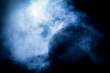 a man in a vietnamese hat in the frost at night around the smoke