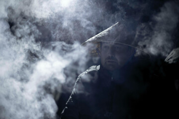 Fototapeta na wymiar a man in a vietnamese hat in the frost at night around the smoke