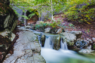 Fototapeta premium Beautiful stone bridge and waterfall in the woods