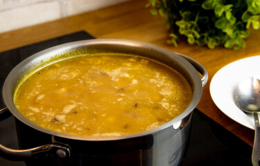 selective focus on lentil and pea soup in a steel pot on the hob