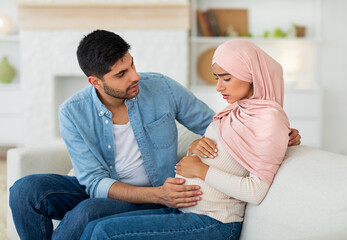 Care in couple during pregnancy. Worried arab husband supporting pregnant wife with prenatal...
