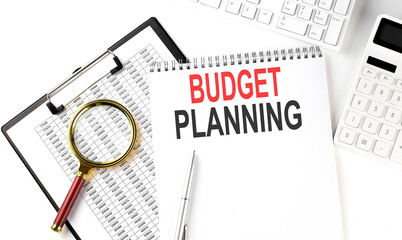 Office desk table with keyboard, notepad ,chart and calculator. Top view with text BUDGET PLANNING