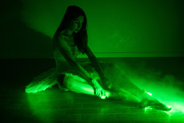 Ballerina with long legs posing in green light