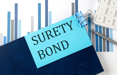 SURETY BOND on sticky note on the notebook on the chart background