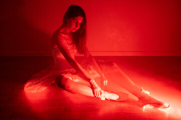 Ballerina with long legs posing in red light