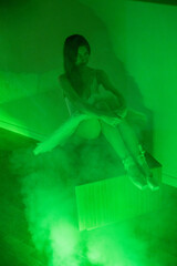 Ballerina with long legs posing in green light