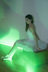Ballerina with long legs posing in green light