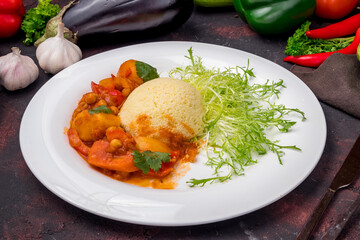 couscous with vegetables on white plate on dark table