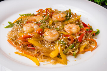 fried Rice noodles with shrimp and vegetables funchosa on dark table macro close up