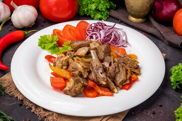 Kebab from lamb ribs with vegetables on plate on dark table