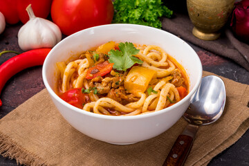 Lagman asian soup with meat, vegetables and noodles, dark table, uzbek cuisine