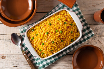 Traditional Mexican rice served with green peas on wooden table