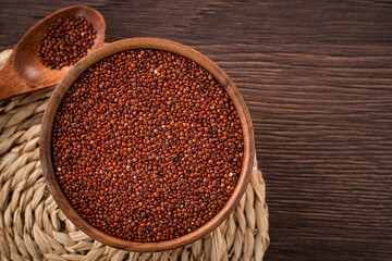 Organic red quinoa in a bowl on wooden table background.