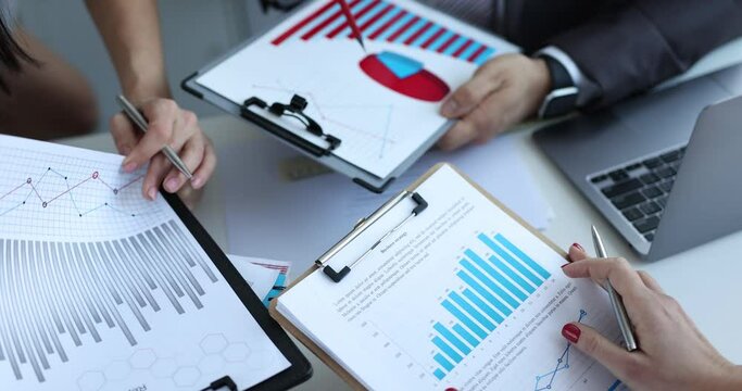 Business people brainstorm papers financial reports or sales charts in meeting