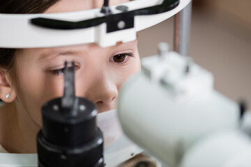 cute child measuring eyesight on blurred autorefractor.