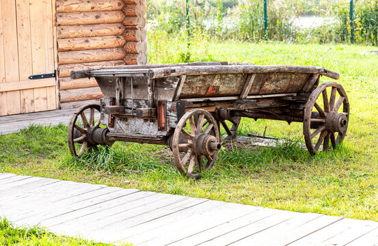 An old cart stands near a wooden house